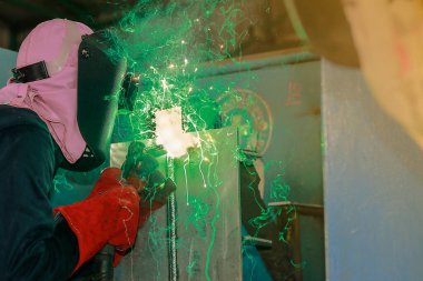 Koruyucu eldivenler ve kaynak maskesiyle çalışan bir işçi