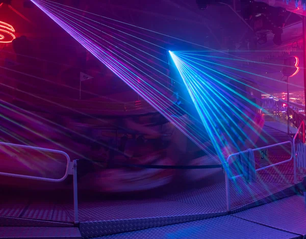 Laser beams of cold blue and purple colors animate a thrill ride on a purple luminous background