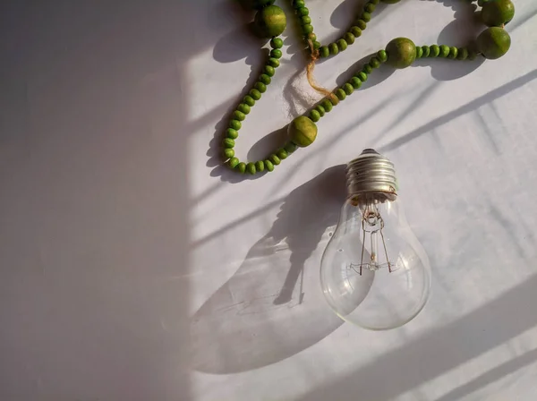 Flat lay photo of green tasbih seed and light bulbs.