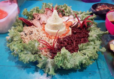 Taze sebzelerle süslenmiş sarı pirinçten yapılmış Endonezya yemekleri.