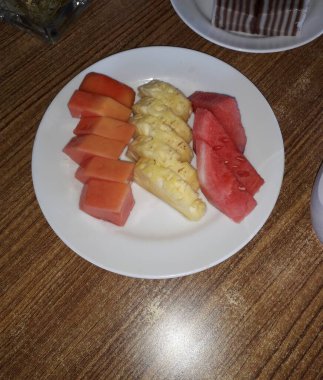 Tahta arka planda bir kase sağlıklı taze meyve salatası. Üst görünüm.