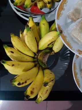 Taze muzlar büyük masada düzgünce düzenlenir. Tabakta bir muz tarağı.