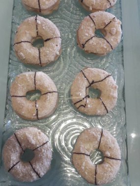 Çörekler, ortasında bir delik olan yuvarlak bir ekmekten yapılır ve sonra ekmek kırıntılarıyla kaplanıp beyaz şekerle kaplanır.