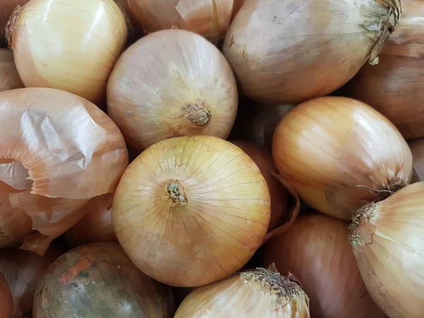 Close up on a flat lay of yellow onions. A day at the farmers market in the summer. Some onions are peeled and others are not.