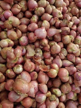 Yakın çekim organik kırmızı soğan yığını mağazada sergileniyor. Taze kırmızı soğan kırıntısı. Süpermarkette toptan satılacak yeni ekin soğanlarının olgunlaşması. Tarım geçmişi.