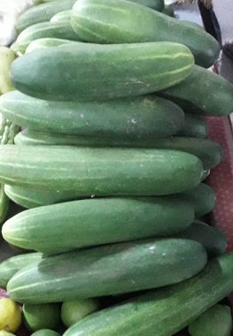 Yığınla yeşil, küçük, dikenli salatalık bir markette üst üste yatıyor.