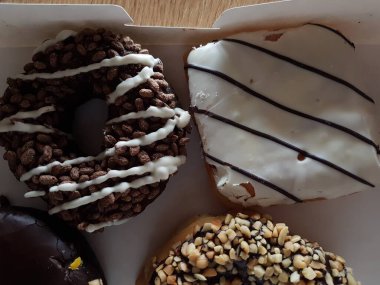 Kutuda renkli çörekler. Jöleli şekerli tatlı yiyecekler, çikolatalı donutlar. Kopyalama alanı olan üst görünüm