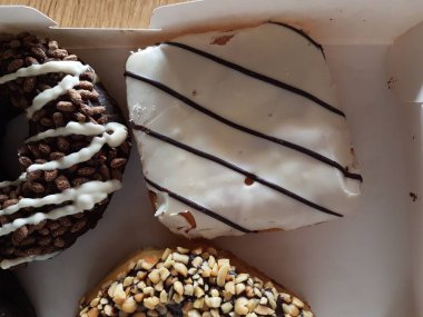 Kutuda renkli çörekler. Jöleli şekerli tatlı yiyecekler, çikolatalı donutlar. Kopyalama alanı olan üst görünüm