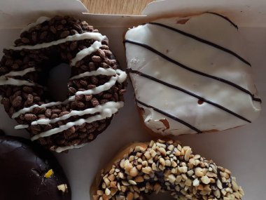 Colorful donuts in a box. Sweet icing sugar food with glazed sprinkles, doughnut with chocolate frosting. Top view with copy space