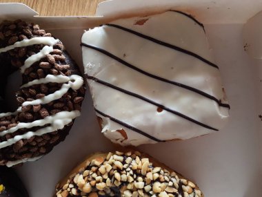 Kutuda renkli çörekler. Jöleli şekerli tatlı yiyecekler, çikolatalı donutlar. Kopyalama alanı olan üst görünüm