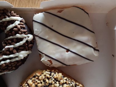 Kutuda renkli çörekler. Jöleli şekerli tatlı yiyecekler, çikolatalı donutlar. Kopyalama alanı olan üst görünüm