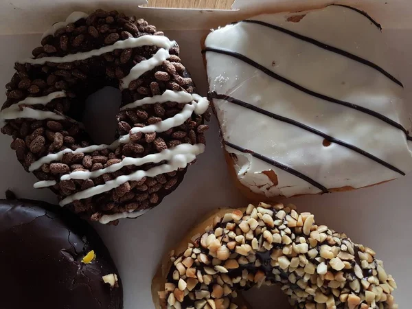 Colorful donuts in a box. Sweet icing sugar food with glazed sprinkles, doughnut with chocolate frosting. Top view with copy space