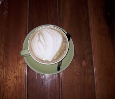 Kahveli sütlü kahve. Aroma kahve fincanı ve kahve çekirdekleri ahşap masada..