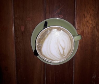 Kahveli sütlü kahve. Aroma kahve fincanı ve kahve çekirdekleri ahşap masada..