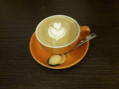 Kahveli sütlü kahve. Aroma kahve fincanı ve kahve çekirdekleri ahşap masada..