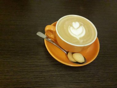 Kahveli sütlü kahve. Aroma kahve fincanı ve kahve çekirdekleri ahşap masada..