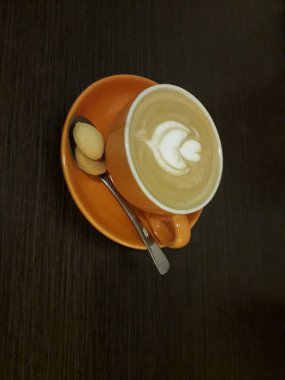 Kahveli sütlü kahve. Aroma kahve fincanı ve kahve çekirdekleri ahşap masada..