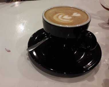 Kahveli sütlü kahve. Aroma kahve fincanı ve kahve çekirdekleri ahşap masada..