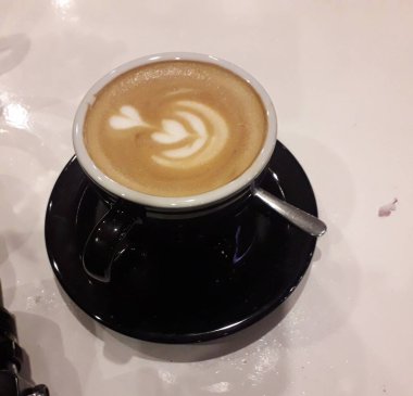 Kahveli sütlü kahve. Aroma kahve fincanı ve kahve çekirdekleri ahşap masada..