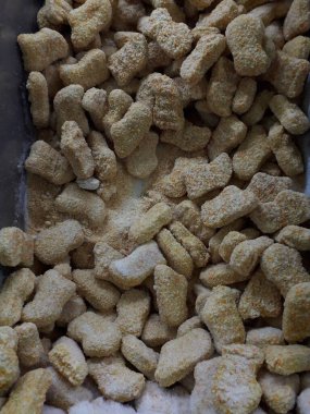Frozen breaded orange chicken nugget sticks texture in the market fridge as a background. Close up photography