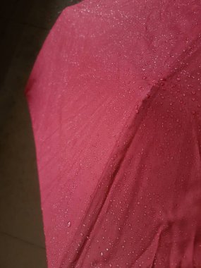 Rain drops on a red umbrella .waterproof fabric background