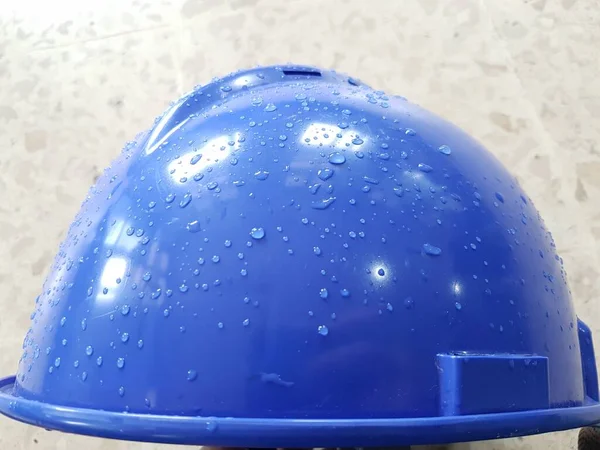 Blue safety helmet place on structure steel at construction site with dew