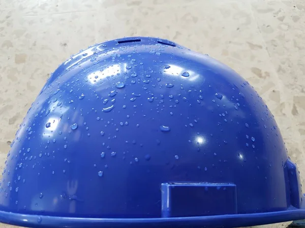 Blue safety helmet place on structure steel at construction site with dew