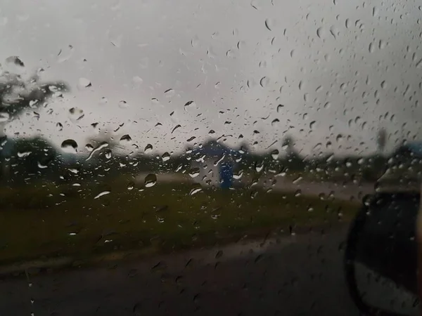 Water droplets on surface of car glass window. Car wash concept. Natural patterns of droplets on windshield. Rain drops wallpaper. Wet windscreen shot during car wash. Selective focus