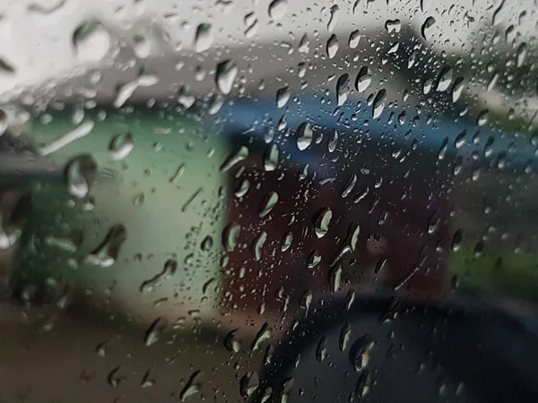 Water droplets on surface of car glass window. Car wash concept. Natural patterns of droplets on windshield. Rain drops wallpaper. Wet windscreen shot during car wash. Selective focus