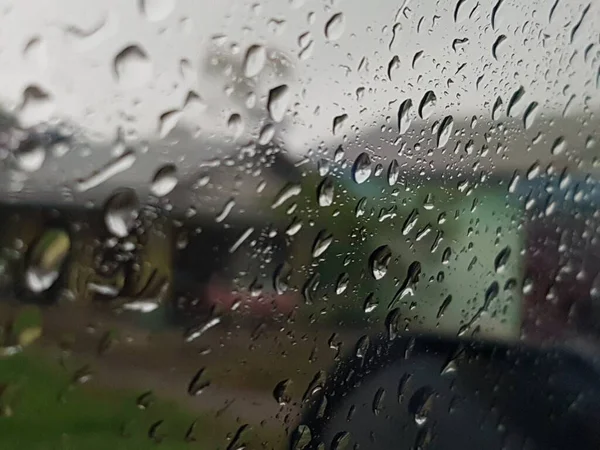 Water droplets on surface of car glass window. Car wash concept. Natural patterns of droplets on windshield. Rain drops wallpaper. Wet windscreen shot during car wash. Selective focus