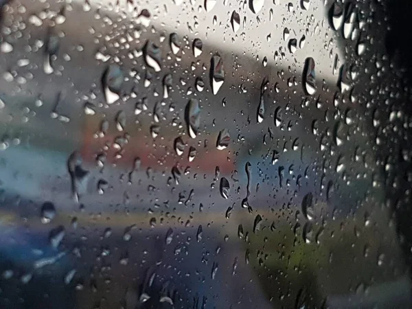 Water droplets on surface of car glass window. Car wash concept. Natural patterns of droplets on windshield. Rain drops wallpaper. Wet windscreen shot during car wash. Selective focus