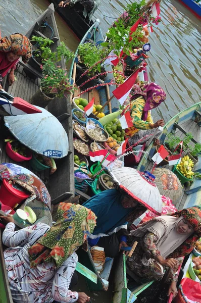 Banjarmasin, South Kalimantan, Indonesia - August 15, 2022 : Women from Lok Baintan joining the Jukung Bungas festival in Banjarmasin. Floating market in Borneo, kalimantan where dealer sell fruit and vegetables