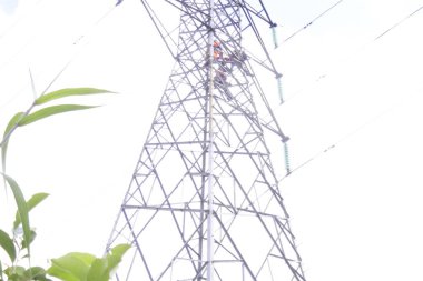 Banjarmasin, Güney Kalimantan, Endonezya - 10 Ağustos 2022: Elektrikçi yüksek voltaj tesislerinde yüksek voltaj kurulumu güvenli ve sistematik olarak bulanık doğal arka plan üzerinde.