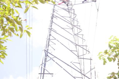 Banjarmasin, Güney Kalimantan, Endonezya - 10 Ağustos 2022: Elektrikçi yüksek voltaj tesislerinde yüksek voltaj kurulumu güvenli ve sistematik olarak bulanık doğal arka plan üzerinde.