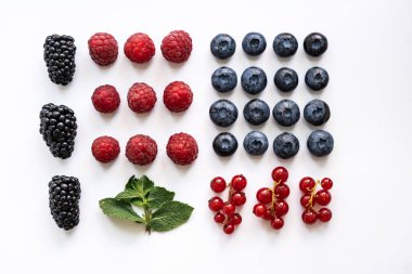 Böğürtlenler, ahududular, yaban mersinleri, nane arkaplanlı kırmızı üzümler hafif arka planda sıralanır.