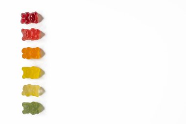 top view of gradient row of gummy bears on light background with negative space