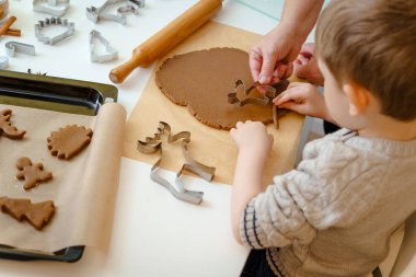 Çocuk hamurdan geyik şeklinde zencefilli kurabiye kesiyor.