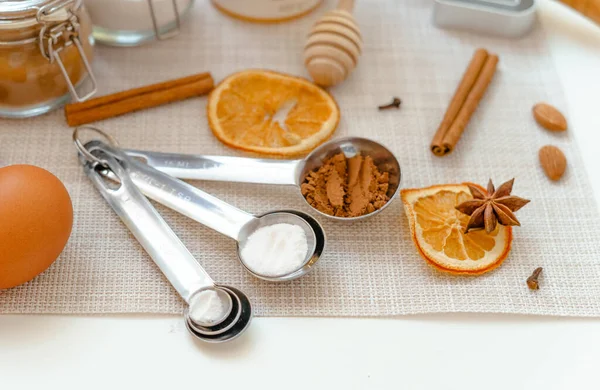 measuring spoons with baking powder, flour and cocoa powder on a white table with kitchen utensils