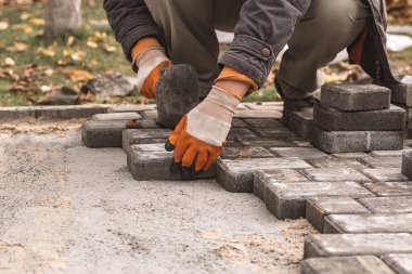 Laying paving slabs close-up. Road surface, construction. Sidewalk repair. Worker laying stone paving slab. Laying tiles in the city park garden .