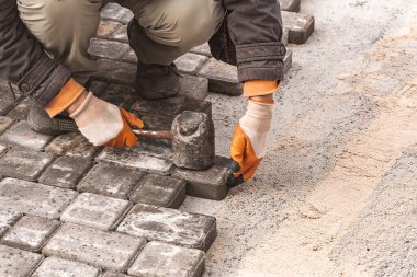 Asfalt döşeme levhaları yakın plan. Yol yüzeyi, inşaat. Kaldırım tamiri. Taş döşeyen işçiler. Şehir parkının bahçesine fayanslar seriyorum. .