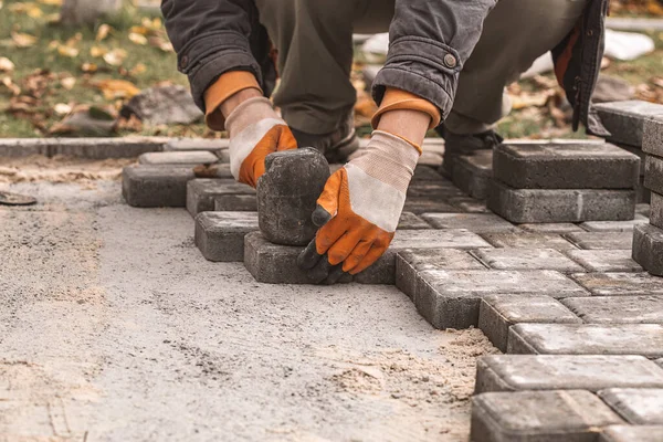 Laying paving slabs close-up. Road surface, construction. Sidewalk repair. Worker laying stone paving slab. Laying tiles in the city park garden .