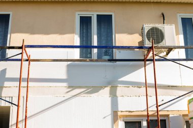 Modern repair and reconstruction of the house. Insulation of the house with polystyrene foam, plastering, applying plaster and painting facade walls using scaffolding when repairing the house. Construction or renovation.