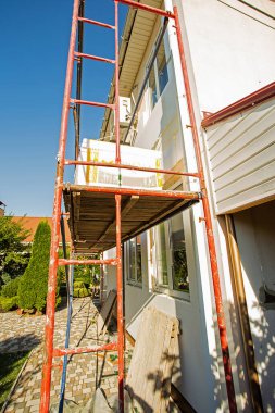 Modern repair and reconstruction of the house. Insulation of the house with polystyrene foam, plastering, applying plaster and painting facade walls using scaffolding when repairing the house. Construction or renovation.