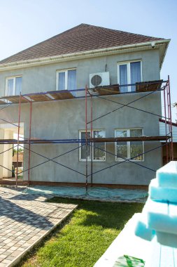 Modern repair and reconstruction of the house. Insulation of the house with polystyrene foam, plastering, applying plaster and painting facade walls using scaffolding when repairing the house. Construction or renovation.