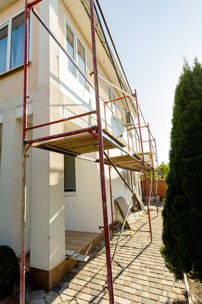 Modern repair and reconstruction of the house. Insulation of the house with polystyrene foam, plastering, applying plaster and painting facade walls using scaffolding when repairing the house