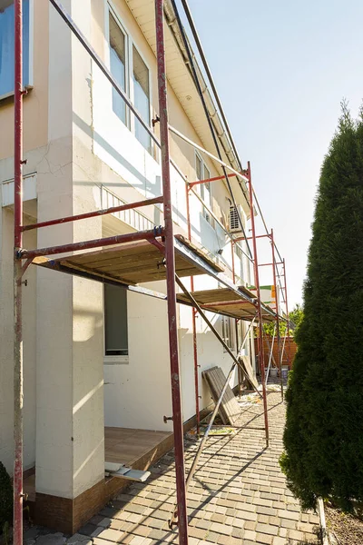 Modern repair and reconstruction of the house. Insulation of the house with polystyrene foam, plastering, applying plaster and painting facade walls using scaffolding when repairing the house