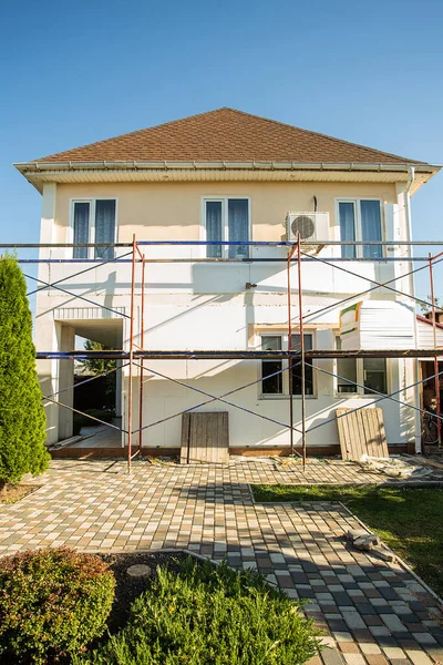 Modern repair and reconstruction of the house. Insulation of the house with polystyrene foam, plastering, applying plaster and painting facade walls using scaffolding when repairing the house