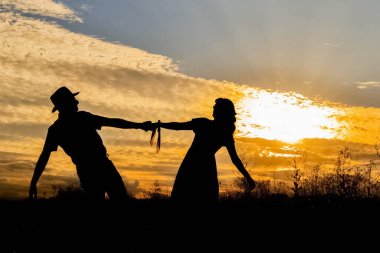 Self-portrait in silhouette of a couple simulating a dance in a sunset.