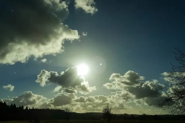 Celestial winter landscape with sun and cumulus clouds.