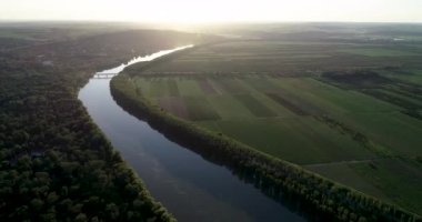 Gün batımında güzel yeşil toprakları olan bir nehir.